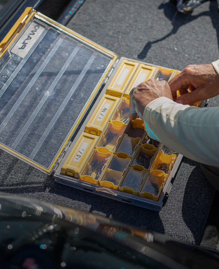 Open plano edge fishing storage box with man putting away supplies